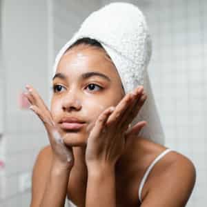 mujer hidratandose la cara para una piel saludable